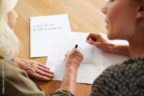 Fotografía Female Friend Helping Senior Woman To Complete Last Will And Testament At Home