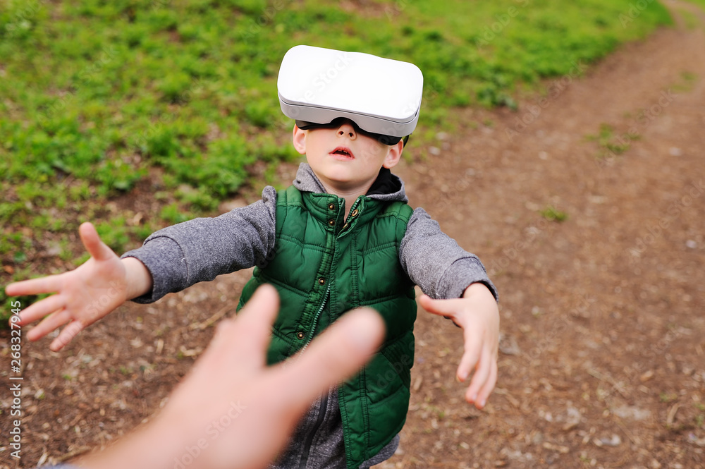 little child boy in glasses virtual reality on the background of greenery and forest. little child boy in glasses virtual reality on the background of greenery and forest.