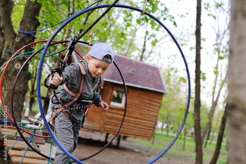 a little boy on an attraction in a rope Park passes an obstacle course