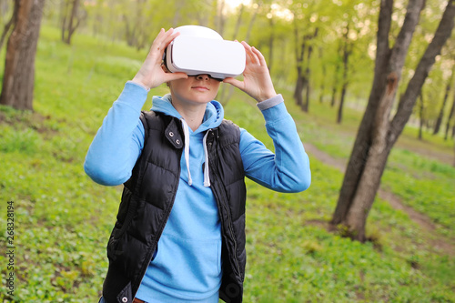 young girl with glasses virtual reality on the background of greenery and Park