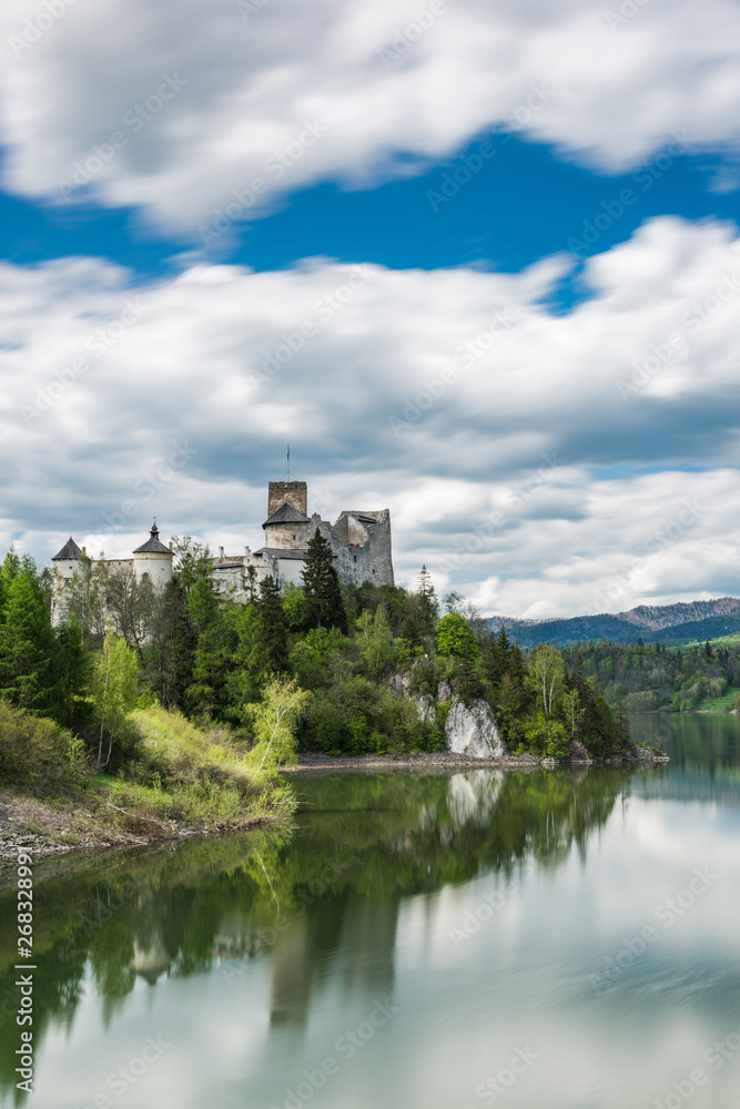 Niedzica castle on hill top, lond exposure motion blur at lake Czorsztyn and clouds on sky