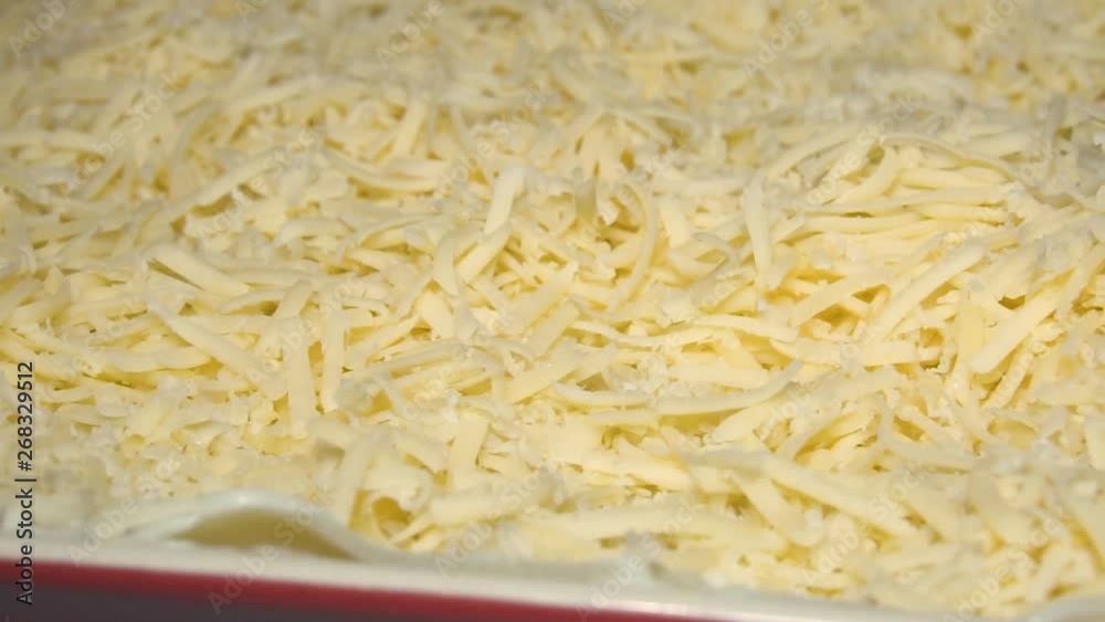 Appetizing meat lasagna is sprinkled with pieces of grated cheese. Parmesan.Very beautiful studio shot. Slow motion. Camera Phantom Flex 4K. Appetizing meat lasagna is sprinkled with pieces of grated cheese. Parmesan.Very beautiful studio shot. Slow motion. Camera Phantom Flex 4K.