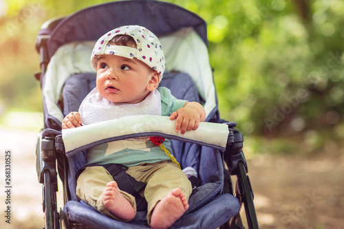 Adorable baby boy sitting in stroller and smiling happily. . © Lucky Fenix