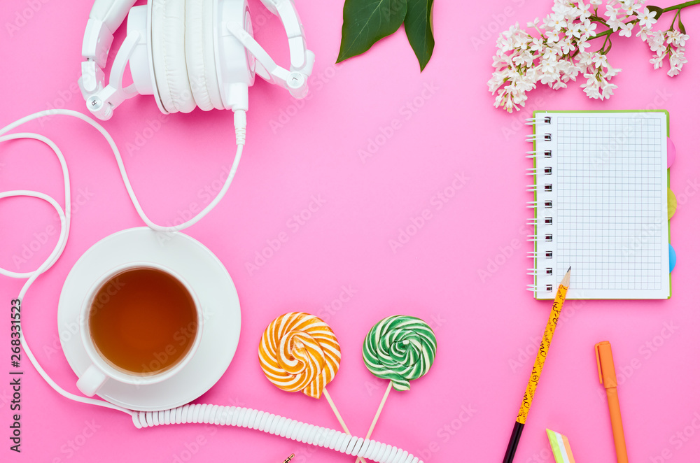 top view of the table of a teenage child, composition of pencil for laptop eraser flower glass with drink earphone Lollipop on pink background