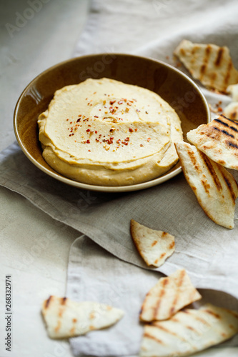 Homemade traditional Middle East appetizer creamy hummus or chickpea dip served with pieces of toasted pita in vintage ceramic plate on white background.Israeli healthy organic vegan appetizer