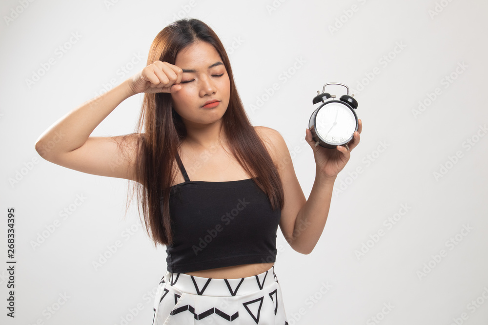 Sleepy young Asian woman with a clock in the morning. Sleepy young Asian woman with a clock in the morning.