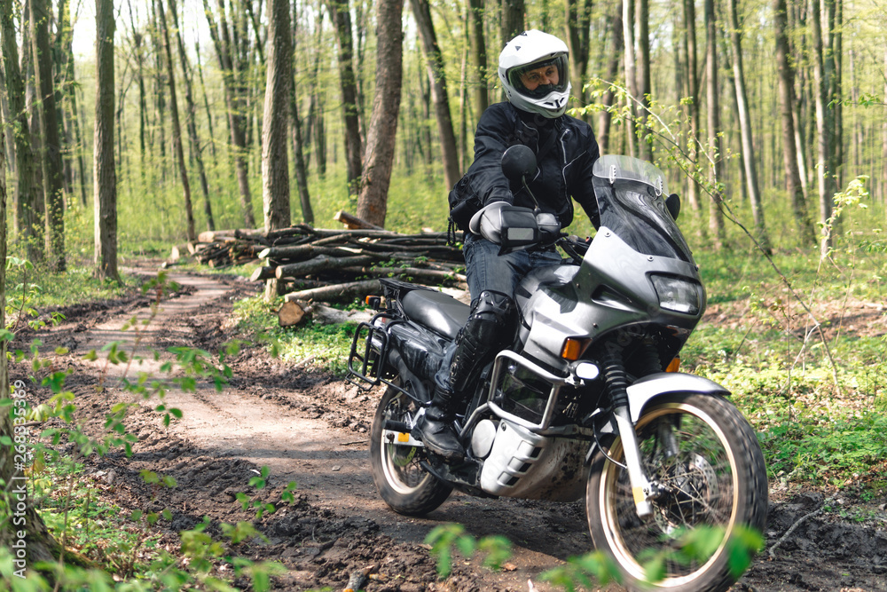 Motorcyclist man in action on Adventure Motorbike. Off road ride. Motorcycle trip. enduro Traveling, Lifestyle Travel dual sport outdoor concept. clothing with protection, forest background Motorcyclist man in action on Adventure Motorbike. Off road ride. Motorcycle trip. enduro Traveling, Lifestyle Travel dual sport outdoor concept. clothing with protection, forest background