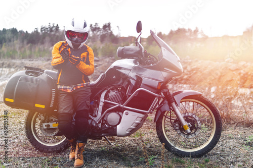 Biker girl wearing a motorcycle outfit, protective clothing, equipment, adventure touristic motorbike with side bags. outdoor travel, active traveler, enduro, off road