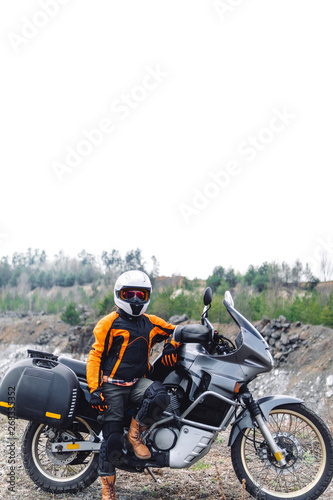 Biker girl wearing a motorcycle outfit, protective clothing, equipment, adventure touristic motorbike with side bags. outdoor travel, active traveler, vertical photo