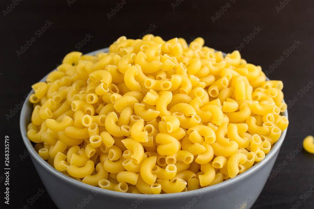 black background with italian raw pasta horns in bowl with copy space black background with italian raw pasta horns in bowl with copy space