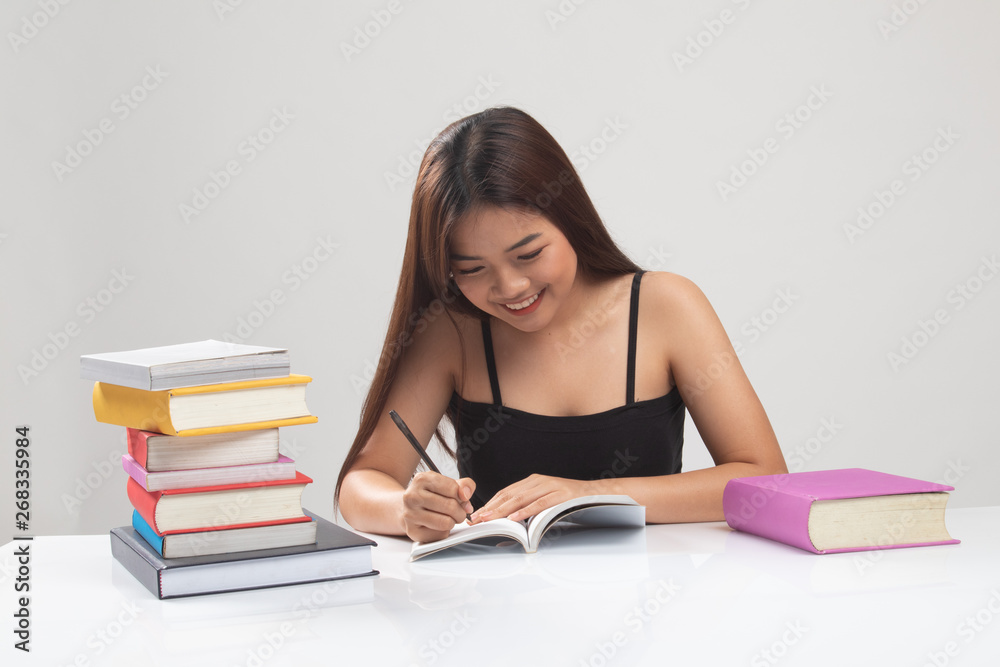 Young Asian woman read a book with books on table. Young Asian woman read a book with books on table.