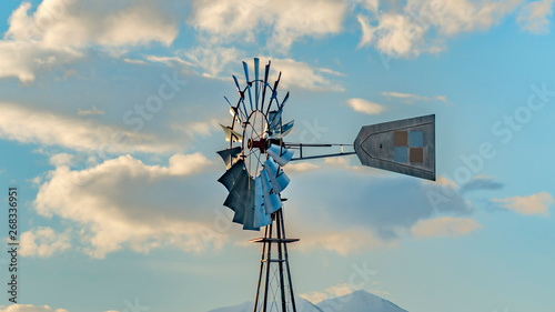 Clear Panorama Windpump with a snow covered mountain and cloudy blue sky in the background