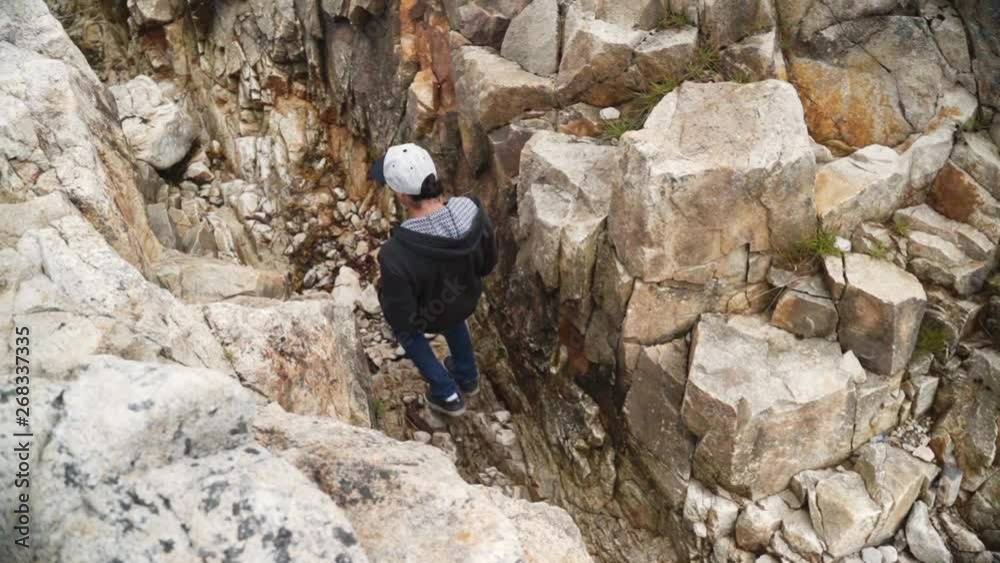 A man seen from above walking inside of a crack in the rocks at the coast of Nova Scotia, Canada - slow motion. A man seen from above walking inside of a crack in the rocks at the coast of Nova Scotia, Canada - slow motion.
