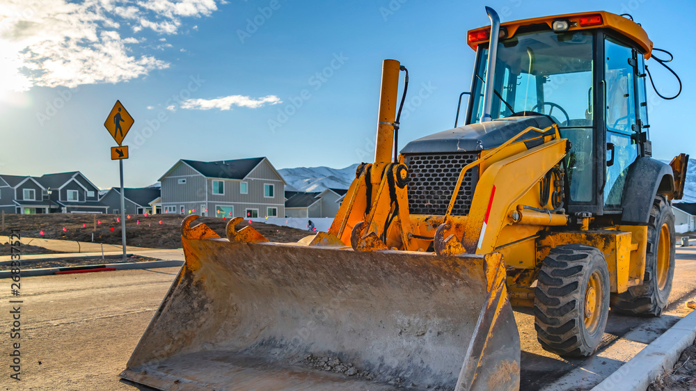 Fototapeta premium Clear Panorama Yellow loader with homes and mountain against blue sky in the background