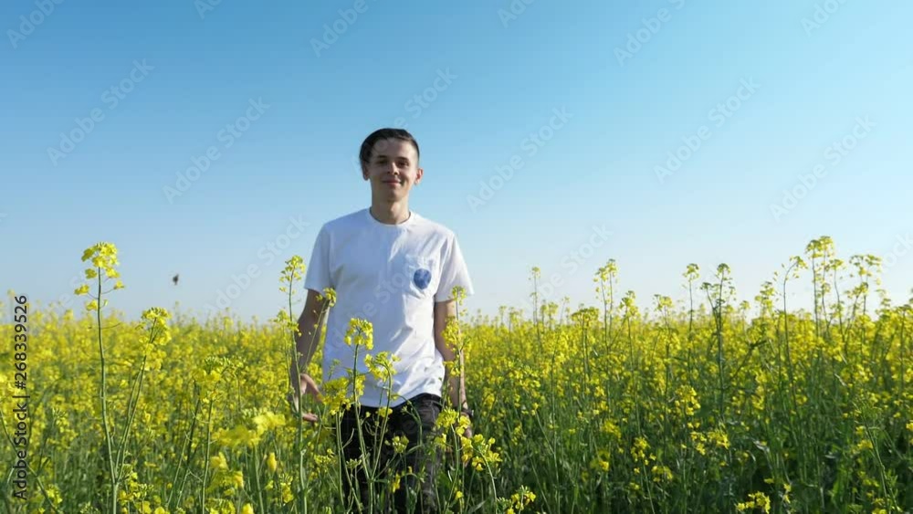 Happy sportive man walking forward in a yellow rapeseed field in slo-mo Happy sportive man walking forward in a yellow rapeseed field in slo-mo