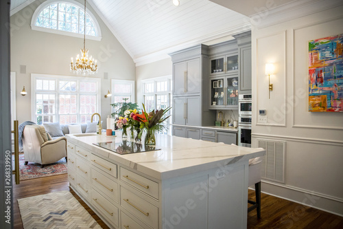Open Concept Elegant and Spacious Kitchen with Marble Countertops, Chandelier, and Two Toned Cabinets