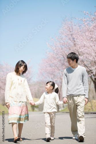桜の前で手をつなぐ親子