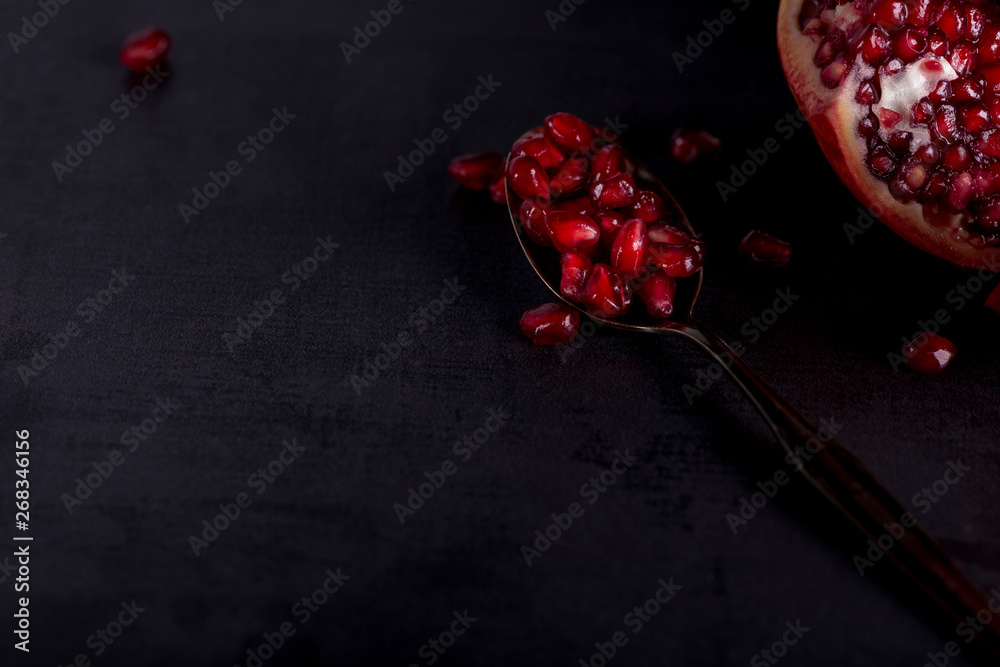 Fresh pomegranate fruits with red seeds on spoon in dark scenery. Fresh pomegranate fruits with red seeds on spoon in dark scenery.