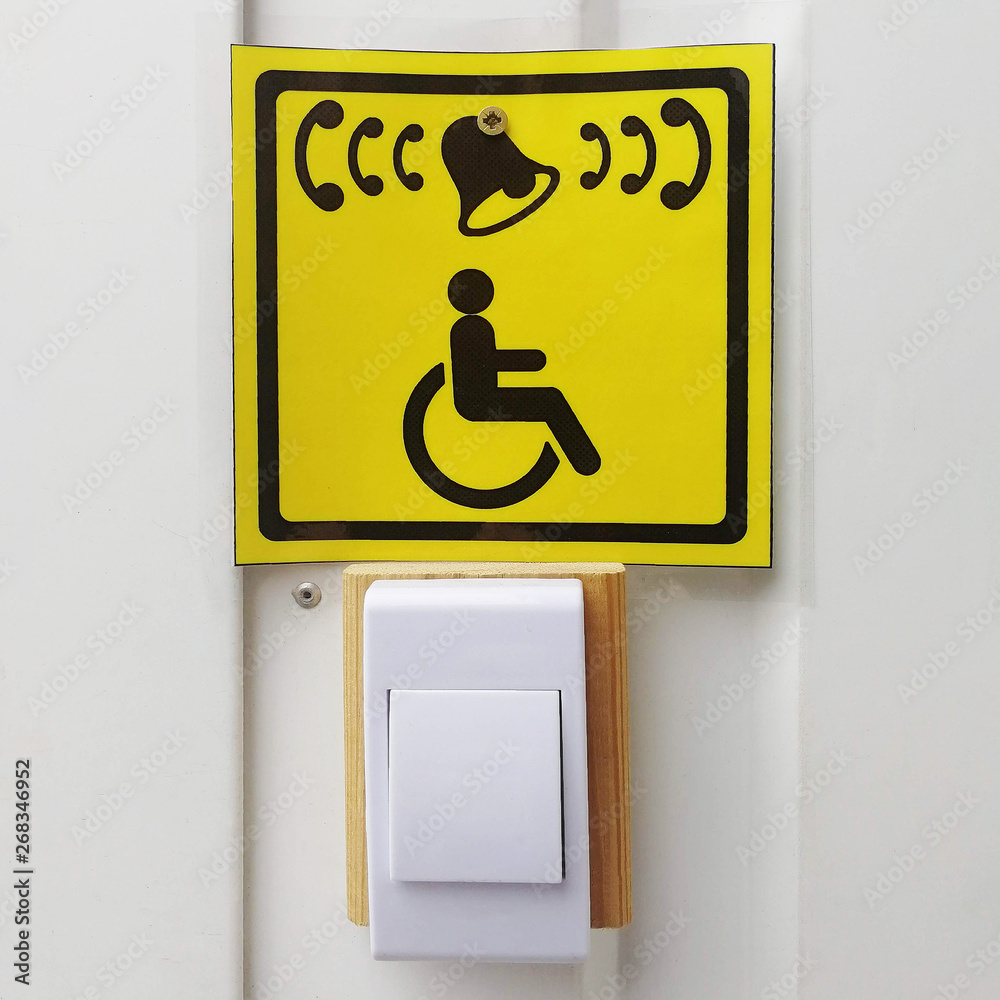 Handicapped call button and yellow sign with icon on white wall Handicapped call button and yellow sign with icon on white wall