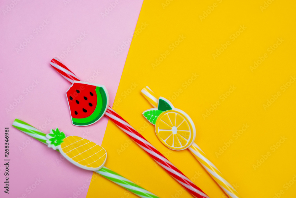 straws in shape of watermelon, lemon and pineapple on a pink and yellow background straws in shape of watermelon, lemon and pineapple on a pink and yellow background