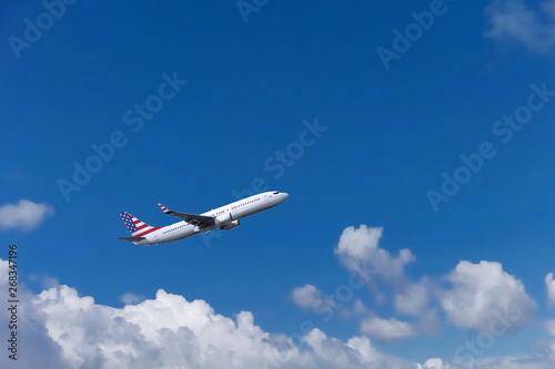 Custom commercial passenger aircraft with american flag on the tail. Blue cloudy sky in the background