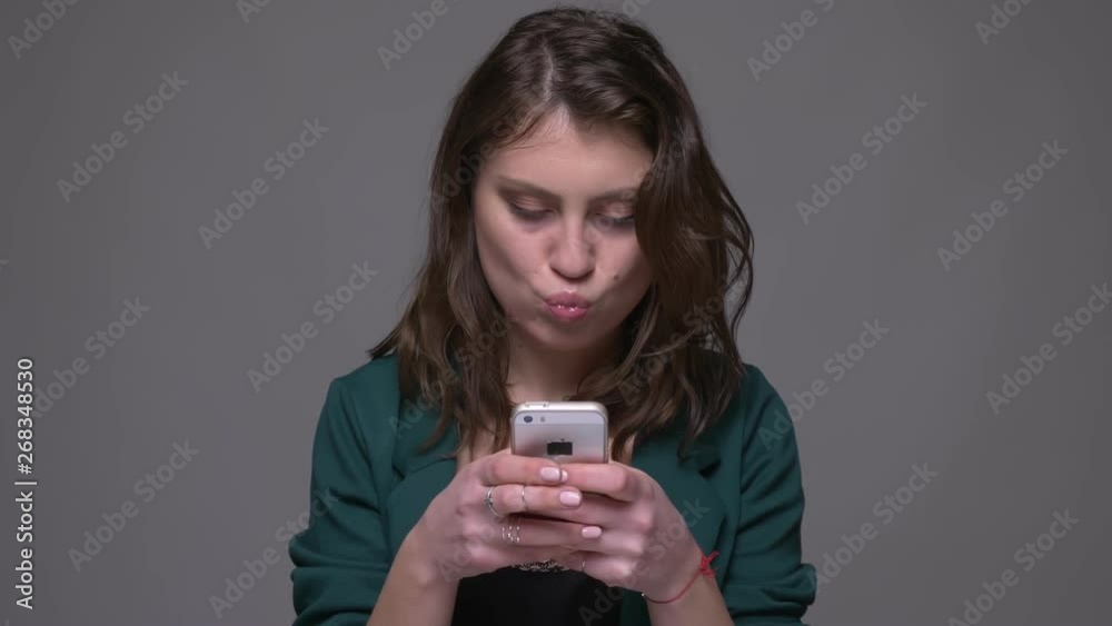Closeup shoot of adult attractive brunette female using the phone with background isolated on gray Closeup shoot of adult attractive brunette female using the phone with background isolated on gray