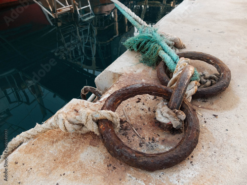 Old rusty mooring rings with tightropes on the edge of a pier