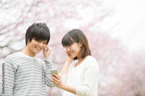 桜の前で音楽を聴くカップル