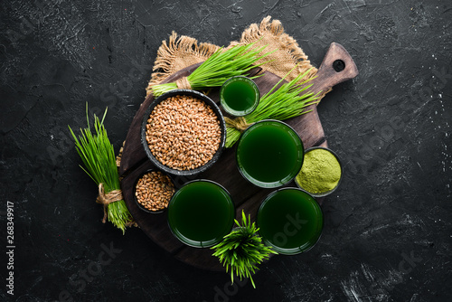 The juice from the green sprouted wheat, and wheat grains. On a black background. Micro Green. Healthy food. Top view. Free space for your text. photo