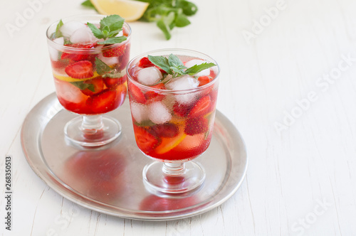  Summer cold drink . Lemonade with mint and strawberries on a light background.