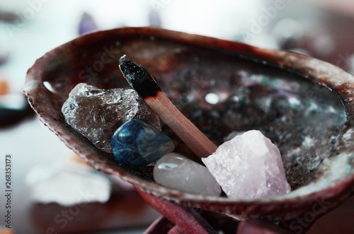 Abalone Shell with Palo Santo, and filled with healing crystals. Rose Quartz, Smokey Quartz, Sodalite, and Clear Quartz.  Burning palo santo in a abalone shell, being held. Variety of crystals shell