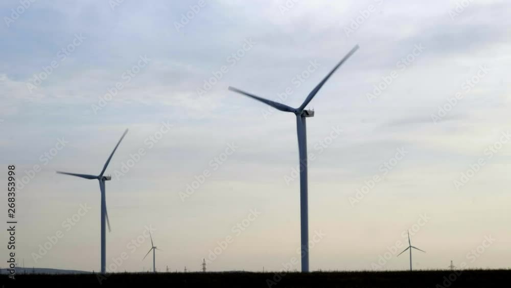 Evening silhouette of windmills with sun setting in background on a cloudy blue sky. These clean energy generating wind farms are densely populated in the state. Evening silhouette of windmills with sun setting in background on a cloudy blue sky. These clean energy generating wind farms are densely populated in the state.