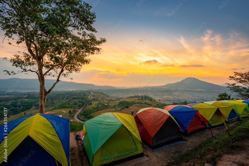 Tents of the tourist set on the mountain. Sunset or sunrise with clouds and Orange light rays. Hiking concept, The adventure tourism.