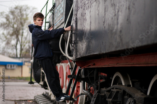Portrait of man student on platform of train station near old train © Svetlana