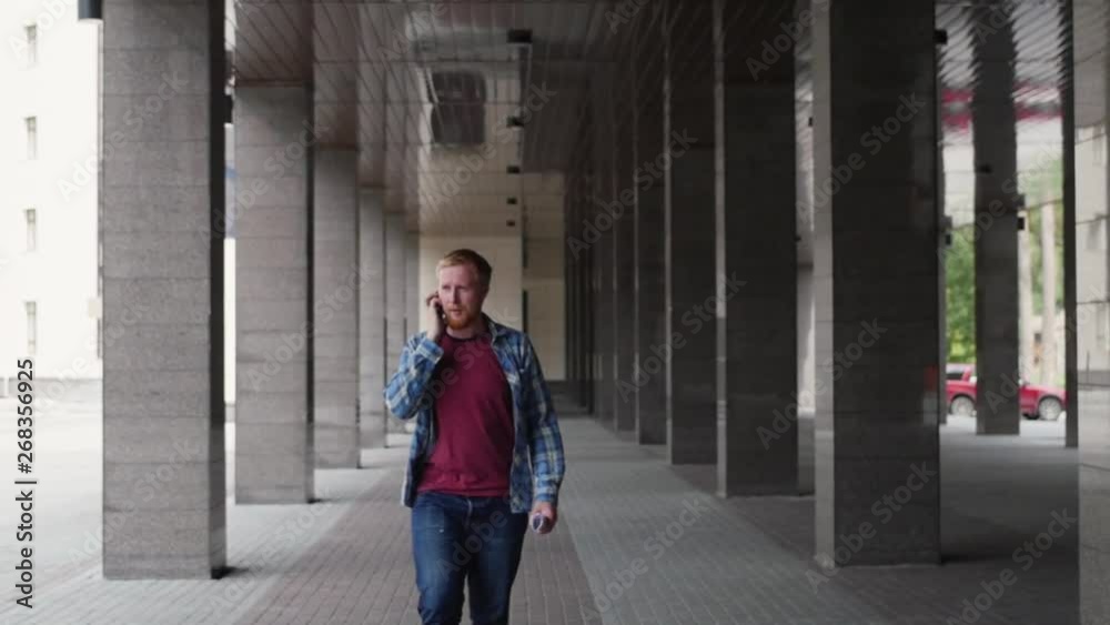 a young student goes to university talking on the phone. young businessman talking on the phone. a man in a plaid shirt goes a young student goes to university talking on the phone. young businessman talking on the phone. a man in a plaid shirt goes