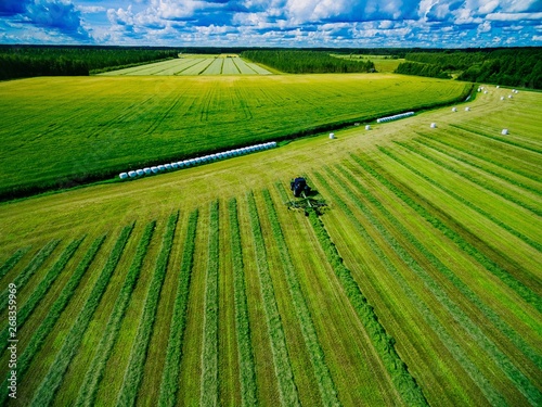 Aerial view of Tractor mowing green field in Finland. © nblxer