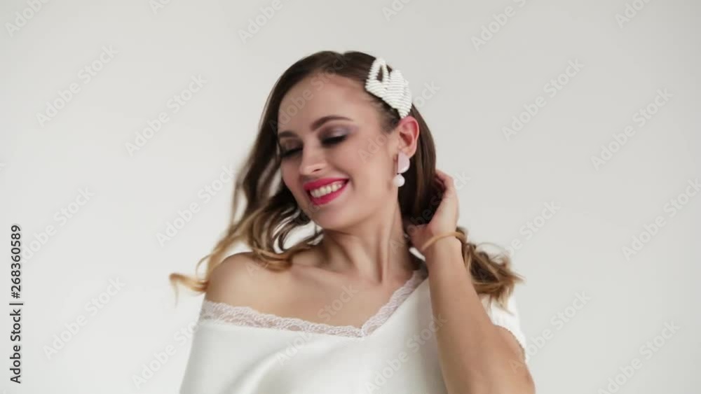 Beautiful girl with gorgeous smile and thick hair on white background in white jumper Beautiful girl with gorgeous smile and thick hair on white background in white jumper