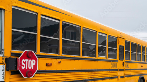 Panorama Side view of a school bus on a road passing through snowy homes in winter