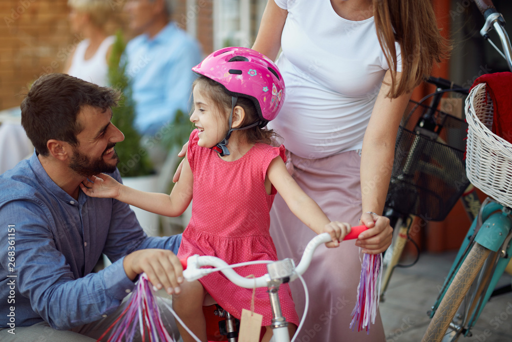 Family buying at happy girl bicycle helmet in bike shop.