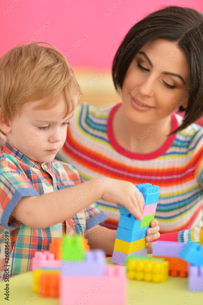 Young mother and cute little son playing with colorful plastic blocks Young mother and cute little son playing with colorful plastic blocks