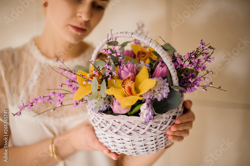 Young girl holding a spring white basket of tender yellow orchids