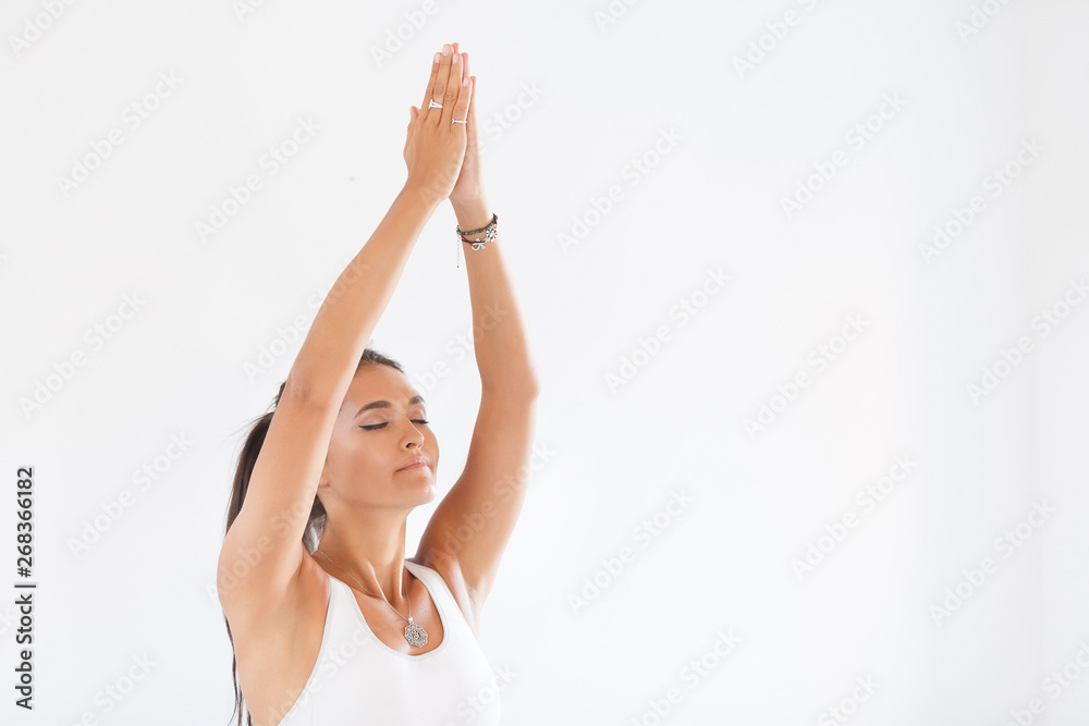 Charming young woman instructor in yoga meditating with closed eyes or close-up hands on white background. Copyspace Charming young woman instructor in yoga meditating with closed eyes or close-up hands on white background. Copyspace