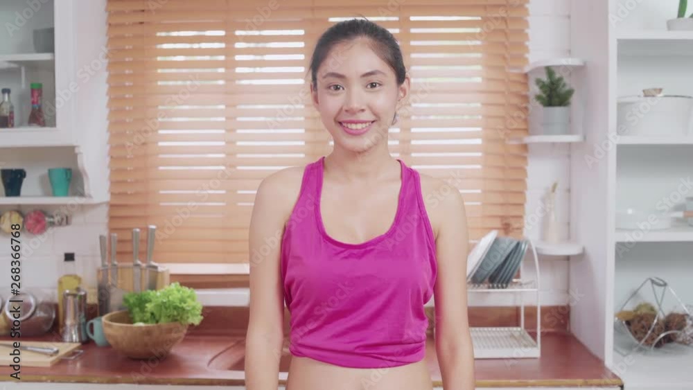 Young Asian blogger woman exercise and looking to camera in kitchen, Attractive beautiful female working out for healthy at home. Woman exercise at home concept. Young Asian blogger woman exercise and looking to camera in kitchen, Attractive beautiful female working out for healthy at home. Woman exercise at home concept.