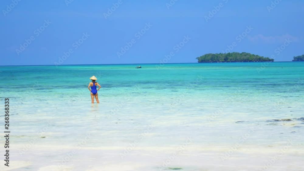 Slow motion: woman sunbathing in turquoise water white sand beach tropical coastline Wab Kei Islands Indonesia paradise travel destination sunny hot day Slow motion: woman sunbathing in turquoise water white sand beach tropical coastline Wab Kei Islands Indonesia paradise travel destination sunny hot day