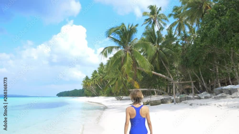 Slow motion: woman sunbathing walking on white sand beach turquoise water tropical coastline Wab Kei Islands Indonesia paradise travel destination sunny hot day Slow motion: woman sunbathing walking on white sand beach turquoise water tropical coastline Wab Kei Islands Indonesia paradise travel destination sunny hot day