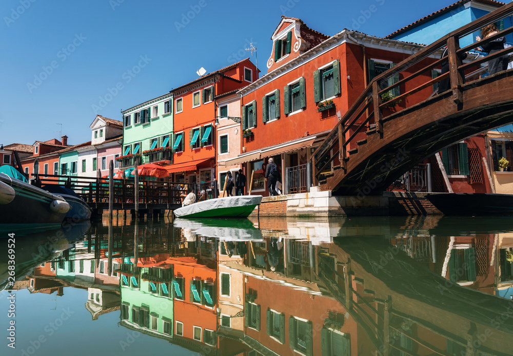 Colorful houses in Burano with reflection in canal, Venice, Italy
