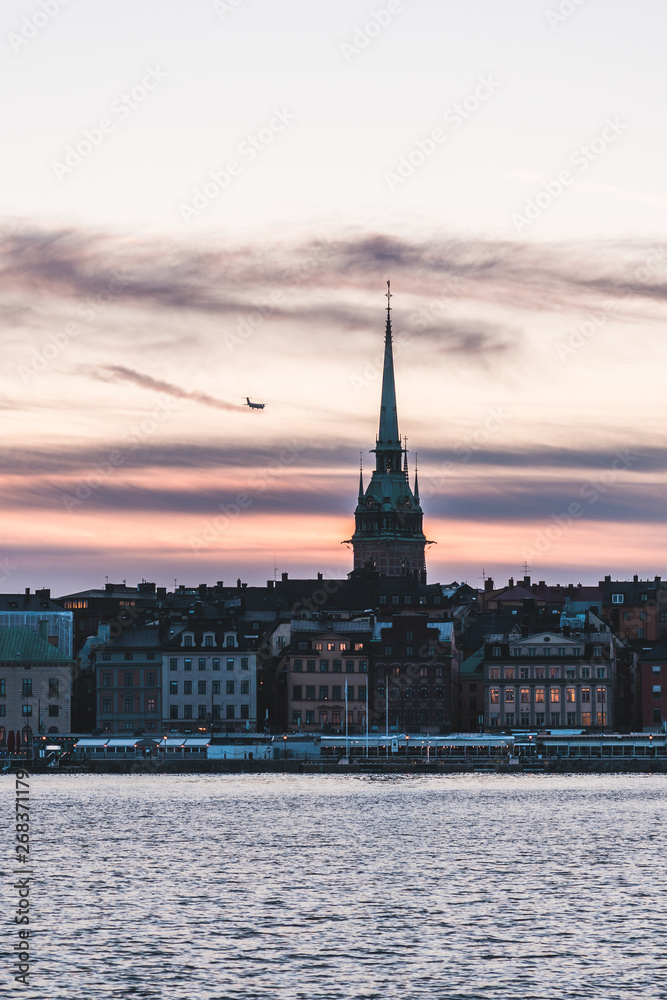 View of the old town with an airplane flying by as the sun is going down, Stockholm Sweden