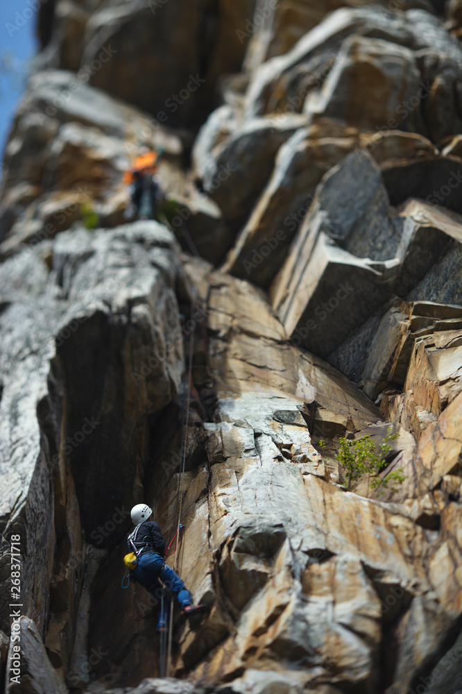 Climber climbs up the rope against the backdrop of overhanging rocks. Tilt-Shift effect. Climber climbs up the rope against the backdrop of overhanging rocks. Tilt-Shift effect.