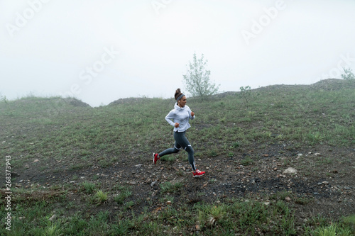 Above view of motivated female runner during foggy morning in nature.