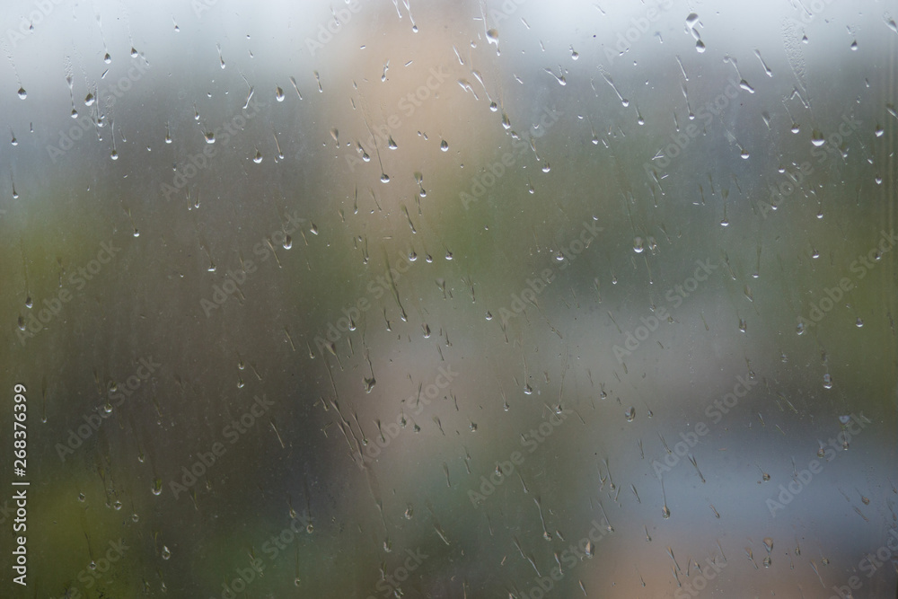 Rain drops running down dirty glass window pane. Summer time